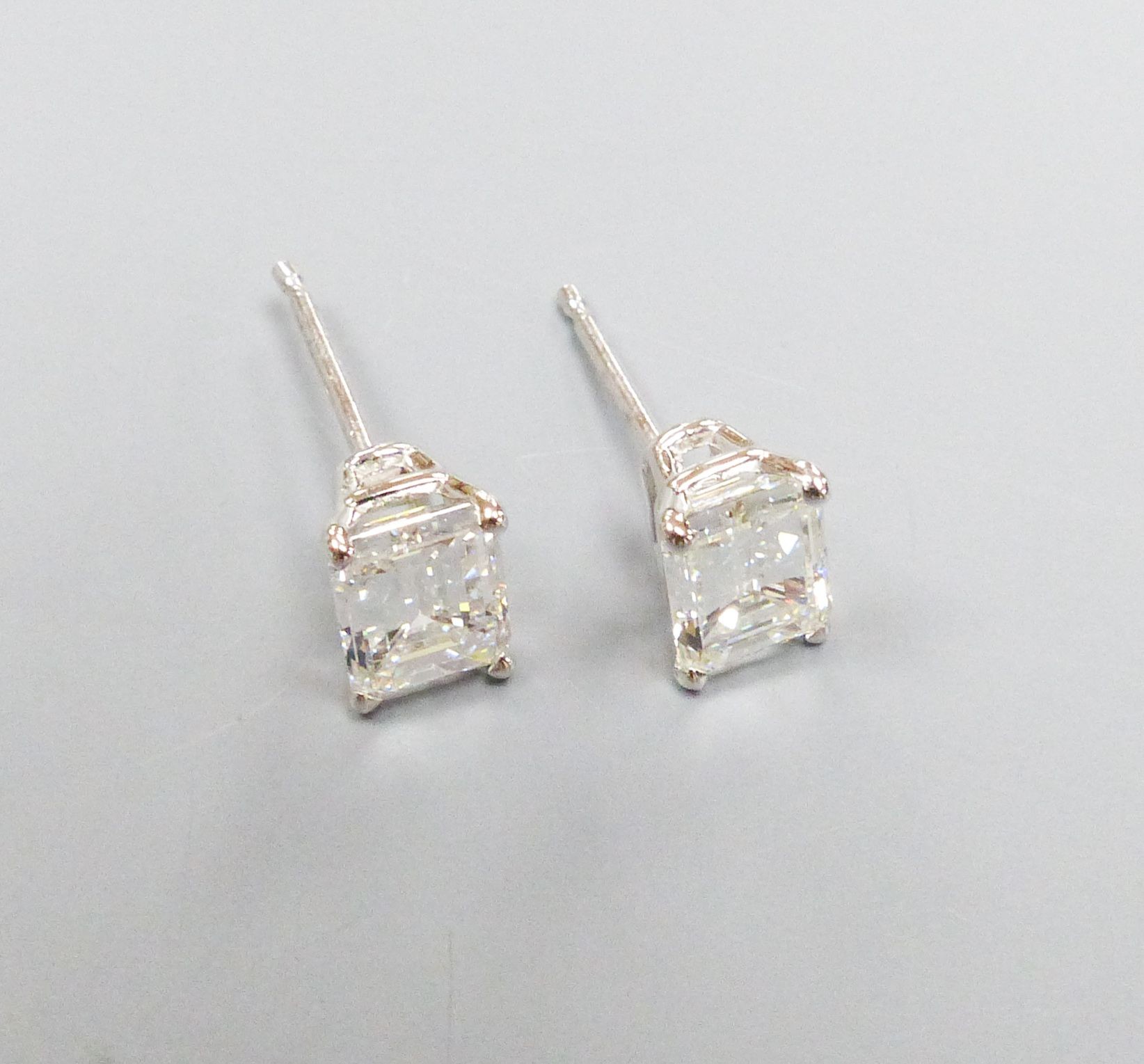 A modern pair of white metal and solitaire emerald cut diamond set ear studs, gross weight 1.1 grams